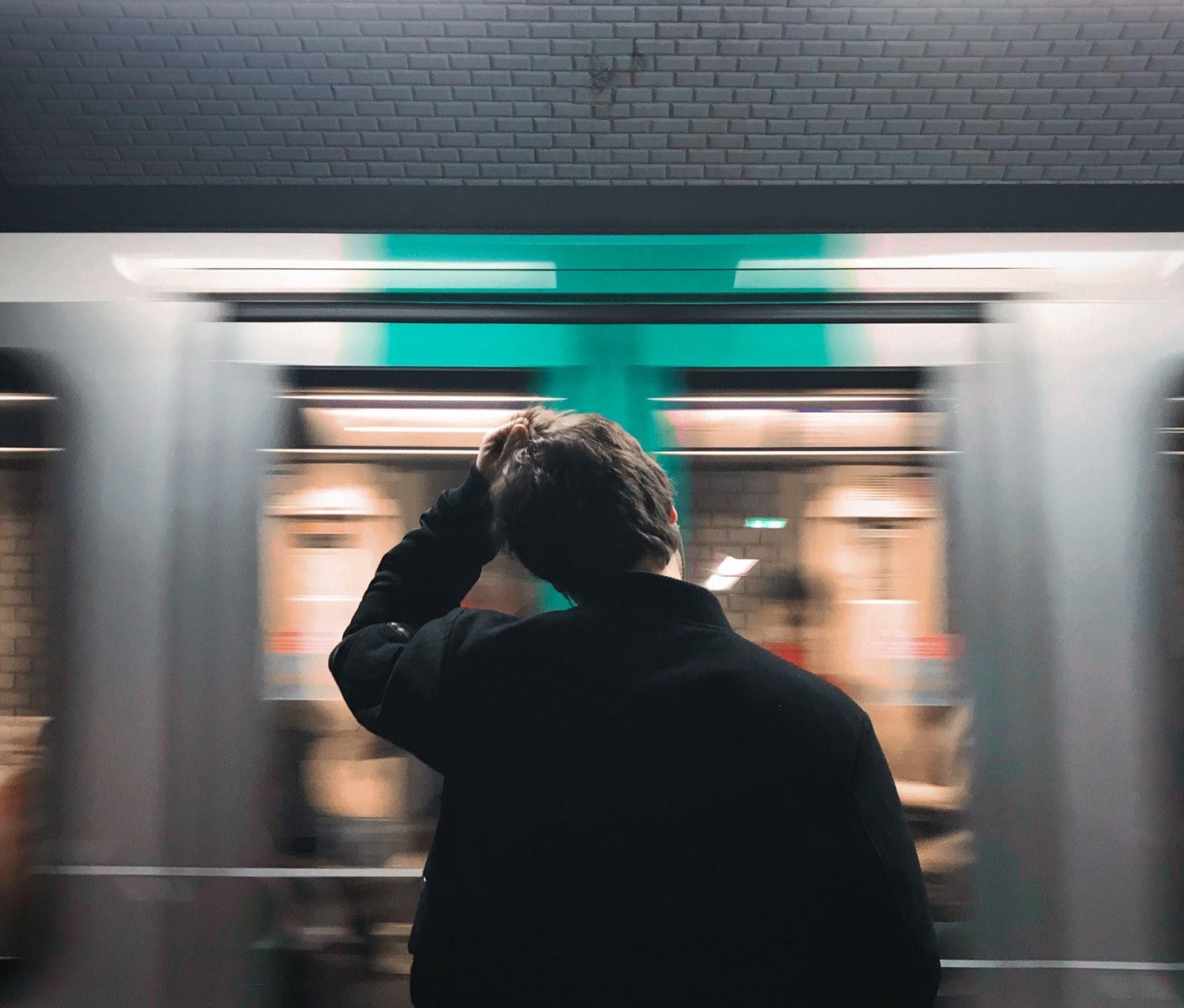 Man wrijft door zijn haar heen terwijl er een metro voor zijn neus wegrijd