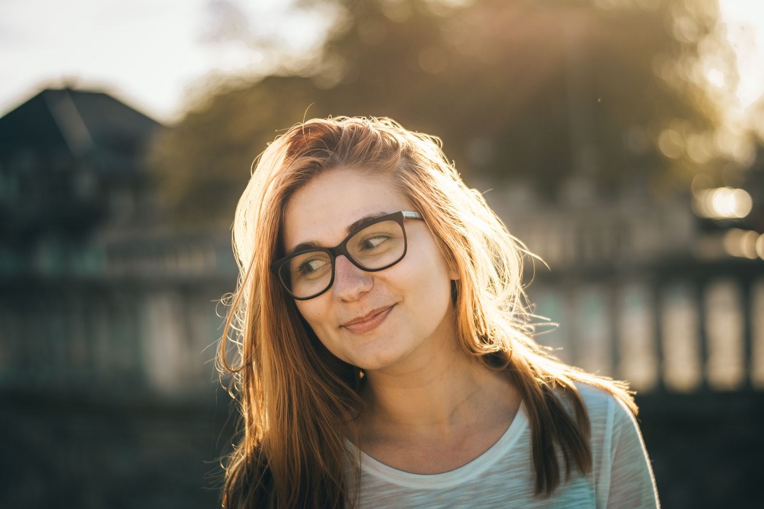 Een vrouw met oranje haren en een bril kijkt tevreden