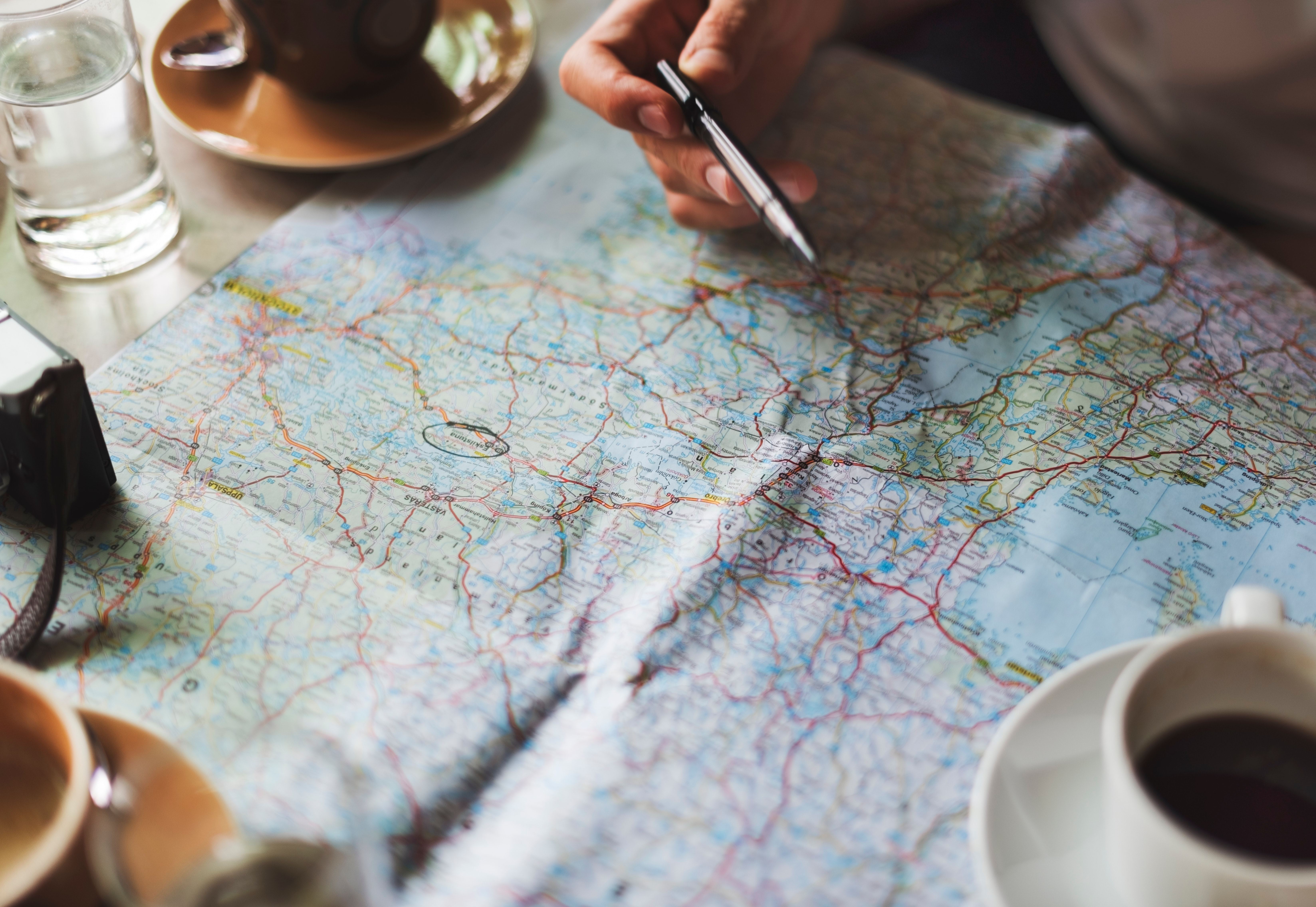Landkaart met de bestemming omcirkeld en een vrouw met een pen in haar hand