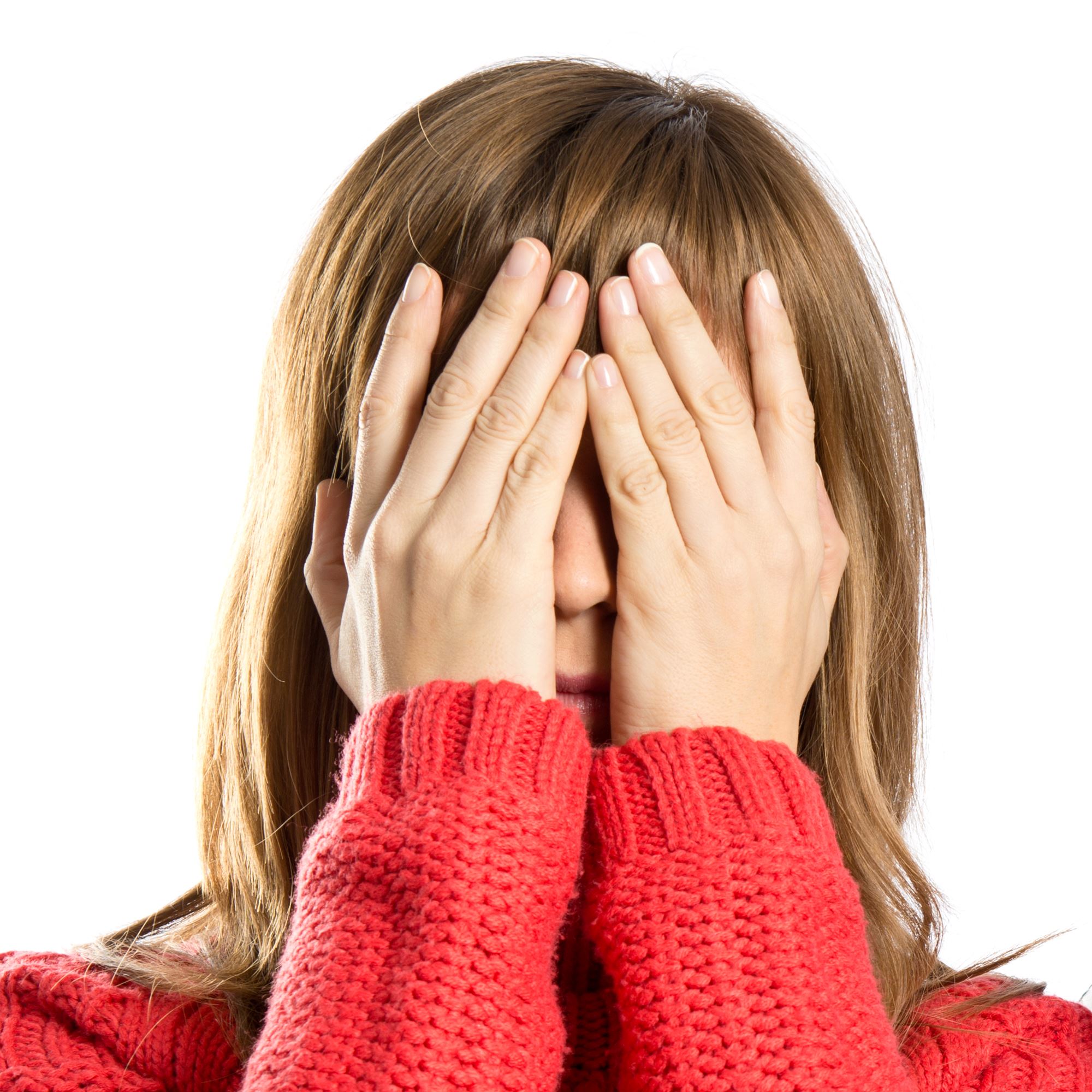 Een vrouw met een rode trui en bruine haren heeft haar handen voor haar ogen.