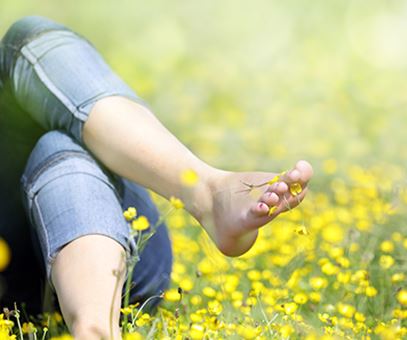 Een vrouw ligt in het gras tussen de boterbloempjes.