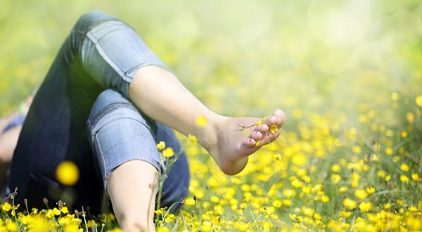 Een vrouw ligt in het gras tussen de boterbloempjes.