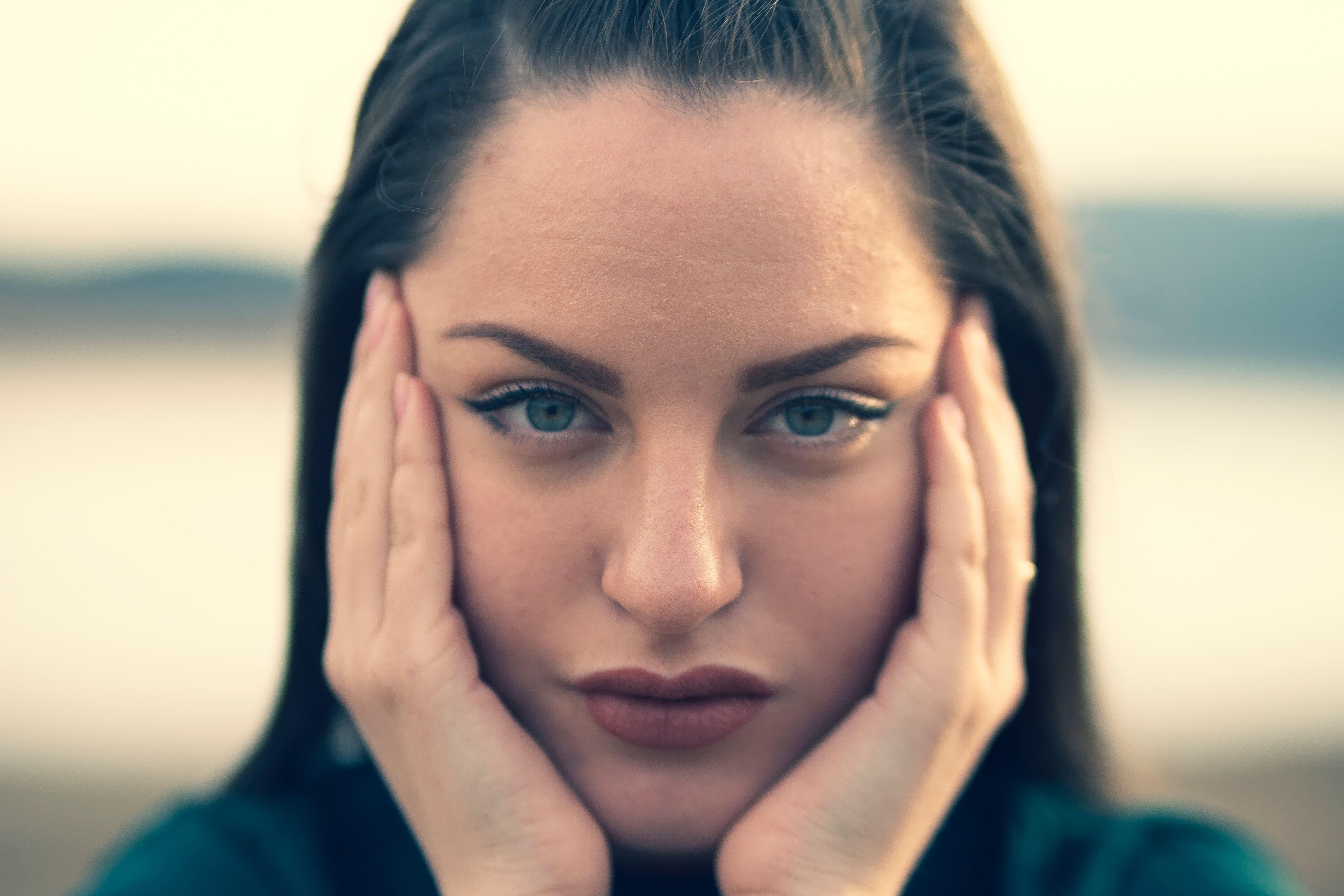 Een vrouw met bruine haren, blauwe ogen en rode lippenstift kijkt heel diep in de camera.