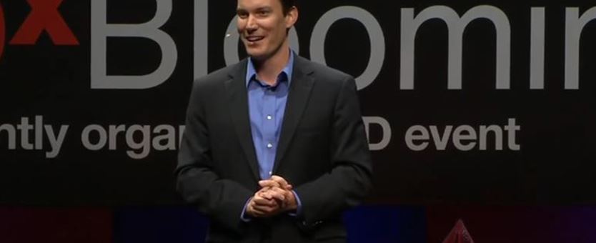 Een man in nette kleding geeft een presentatie.