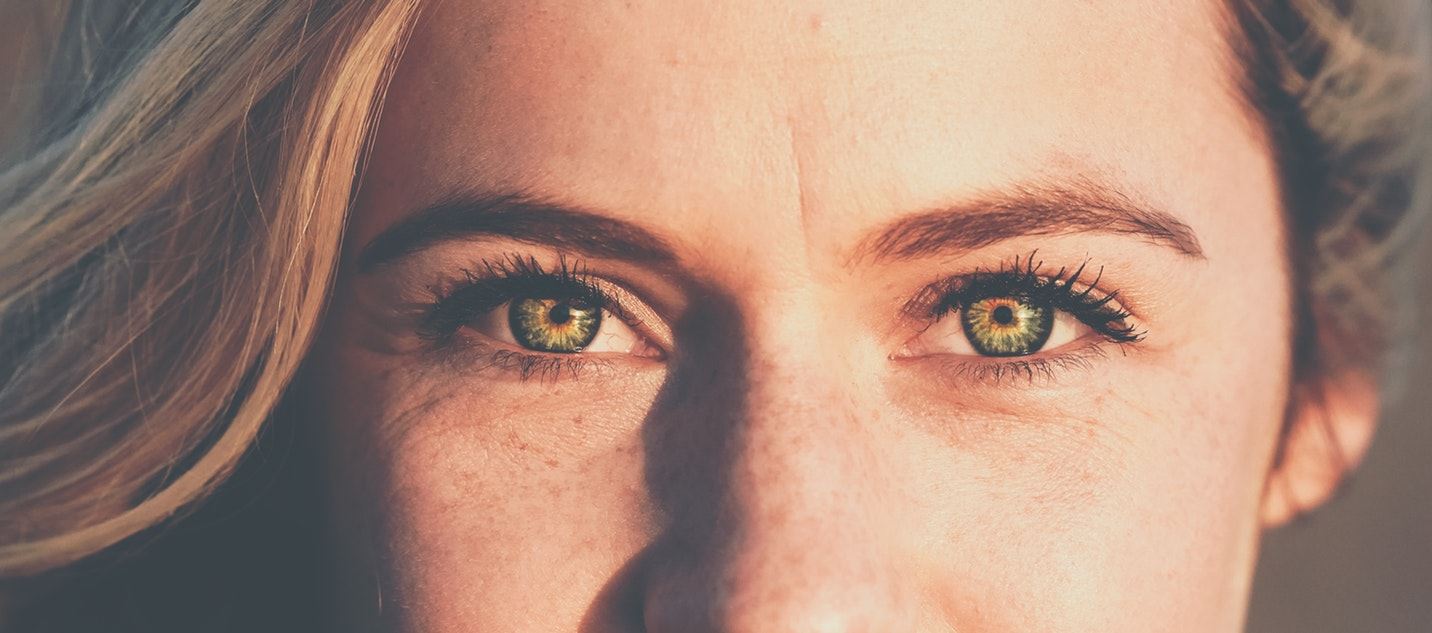 Een close-up van een vrouw met blonde haren en groene ogen.
