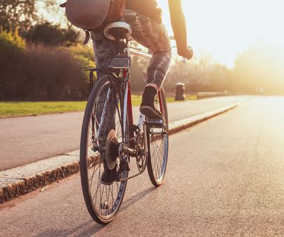 Persoon op fiets fietst door een park met zon op voorgrond