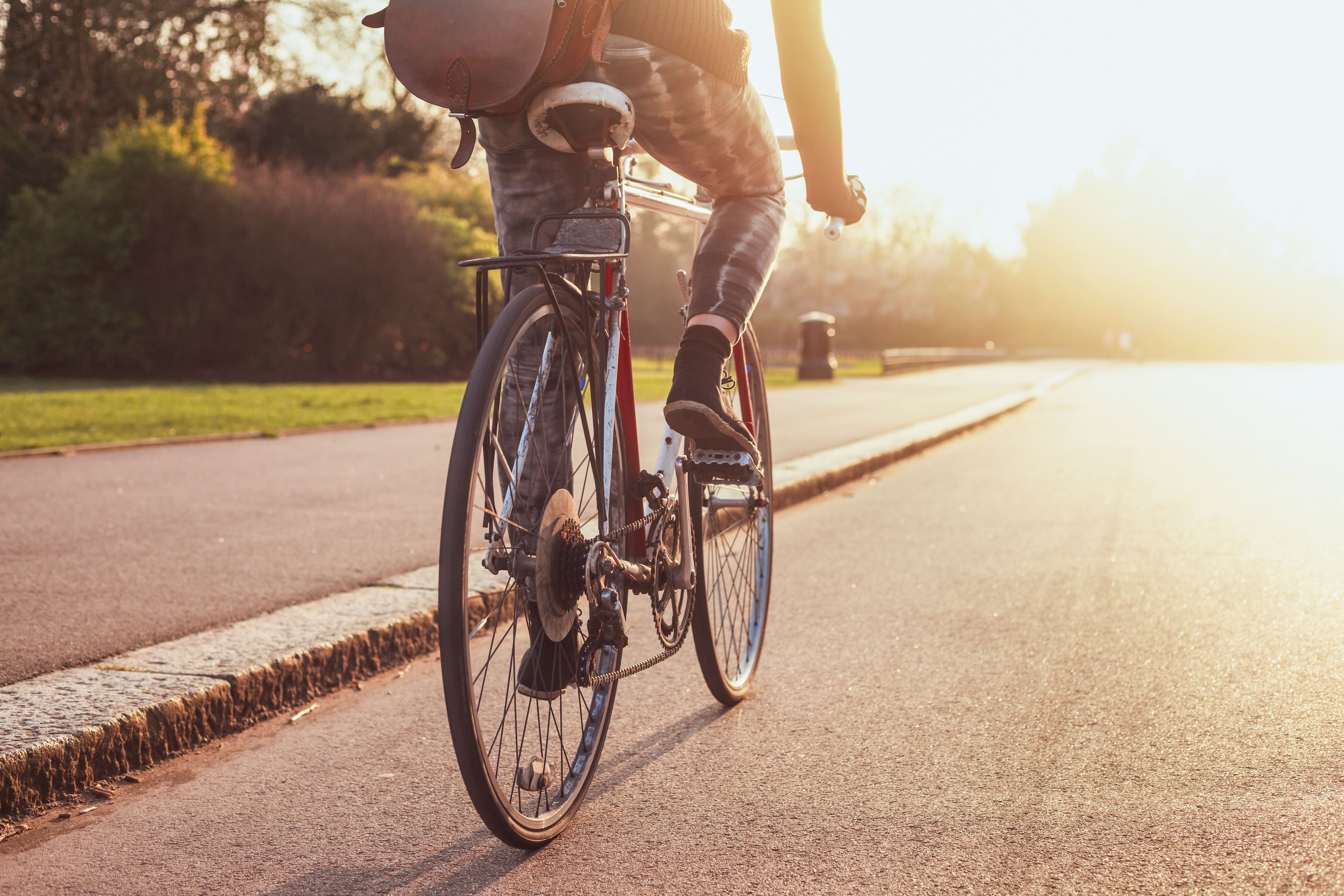 Persoon op fiets fietst door een park met zon op voorgrond