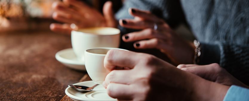 Twee mensen zitten aan een tafel en drinken koffie.