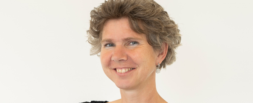 Sandra Doeze Jager, een vrouw met korte grijze haren die haar haar armen over elkaar heeft, lacht in de camera.